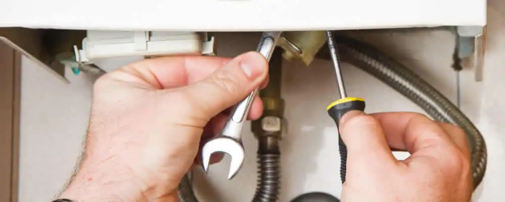 Boiler repair technician tightening pipe fittings and connections in Oakland, CA