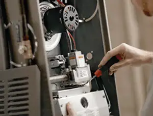 Furnace repair technician inspecting internal components and wiring in Oakland, CA