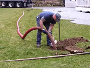 Septic pumping technician servicing a residential septic tank with a vacuum hose in Oakland, CA