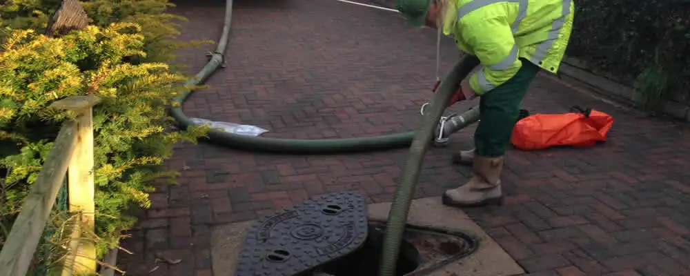 Septic tank cleaning technician servicing a septic tank with a vacuum hose in Oakland, CA