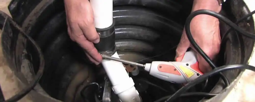 Sump pump installation technician connecting PVC discharge piping in Oakland, CA