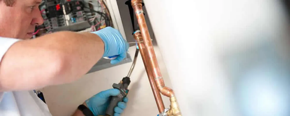 Water heater repair technician testing copper pipe connections and controls in Oakland, CA